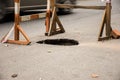 Hole in asphalt on automotive roadway street. Pit in road surface, is surrounded by building fence construction with warning tape Royalty Free Stock Photo