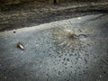 A hole in the asphalt from a whizzbang and the tail part of the projectile nearby Royalty Free Stock Photo