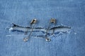 Hole in blue jeans fixed with safety pins Royalty Free Stock Photo