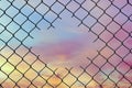 Hole in the center of mesh wire fence on the sky background.