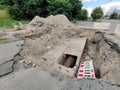 A hole is dug on the road with sewage pipes at the bottom. Repair works of low-quality coating and sewerage Royalty Free Stock Photo