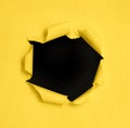 Hole in the paper with torn sides over yellow background Royalty Free Stock Photo