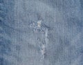 Hole and Threads on Denim Jeans. Ripped Destroyed Torn Blue jeans background. Close up blue jean texture Royalty Free Stock Photo