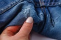 Hole and Threads on Denim Jeans. Ripped Destroyed Torn Blue jeans background. Close up blue jean texture Royalty Free Stock Photo