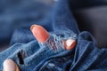 Hole and Threads on Denim Jeans. Ripped Destroyed Torn Blue jeans background. Close up blue jean texture Royalty Free Stock Photo