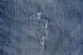 Hole and Threads on Denim Jeans. Ripped Destroyed Torn Blue jeans background. Close up blue jean texture Royalty Free Stock Photo