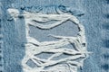 Hole and Threads on Denim Jeans. Ripped Destroyed Torn Blue jeans background. Royalty Free Stock Photo