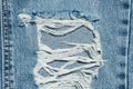 Hole and Threads on Denim Jeans. Ripped Destroyed Torn Blue jeans background. Royalty Free Stock Photo