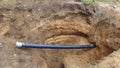 A hole was dug in one of the city streets to repair and replace gas pipes and the pipe is sticking out of the ground. The soil at Royalty Free Stock Photo