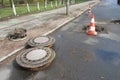 Holes and damage on an asphalt road, secured by red and white shut-off cones because of the risk of accidents