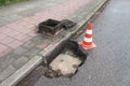 Holes and damage on an asphalt road, secured by red and white shut-off cones because of the risk of accidents