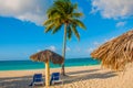 Holguin, Cuba, Playa Esmeralda. Umbrella and two lounge chairs around palm trees. Tropical beach on the Caribbean sea. Royalty Free Stock Photo