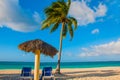 Holguin, Cuba, Playa Esmeralda. Umbrella and two lounge chairs around palm trees. Tropical beach on the Caribbean sea. Paradise la Royalty Free Stock Photo