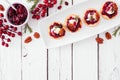 Holiday appetizers with cranberries, goat cheese and pecans, above view top border over a white wood background