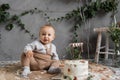 holiday baby's first birthday, boy with a delicious cake sitting on the floor, birthday in rustic style, natural photo
