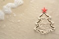 Holiday background - Christmas tree with starfish drawn on a sandy beach Royalty Free Stock Photo