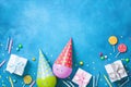 Holiday background with funny balloons in caps, gifts, confetti, candy and candles. Flat lay. Birthday or party greeting card. Royalty Free Stock Photo