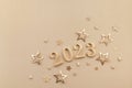 Holiday background with golden Christmas decorations and New year 2023 numbers and confetti stars top view