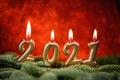 Holiday background Happy New Year 2021. Digits of year 2021 made by burning gold candles on red festive sparkling background Royalty Free Stock Photo