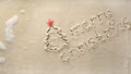 Holiday background - merry Christmas and tree with starfish drawn on a sandy beach Royalty Free Stock Photo