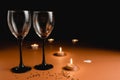Two clinking wine glasses, candle, confetti on orange and black background. Minimal style and valentines day Royalty Free Stock Photo