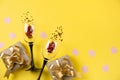 Two clinking wine glasses, various handmade gift boxes decorated with pink heart confetti on yellow background