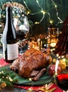 Holiday baked turkey or chicken in honey with apples on red napkin served with glasses, bottle of wine, candles, fir branches,