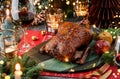 Holiday baked turkey or chicken in honey with apples on red napkin served with glasses, bottle of wine, candles, fir branches,