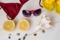 Holiday beach flat lay. Burgundy swimsuit, sunglasses, seashell and pebbles and cut lemon Royalty Free Stock Photo