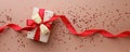 Holiday beige background with gift, red satin bow, ribbon. Valentine`s Day, Happy Women`s Day, Mother`s Day, Birthday, Wedding, Royalty Free Stock Photo
