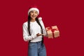 Holiday Bonus. Beautiful Arab Woman In Santa Hat Holding Wrapped Gift Box