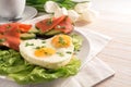 Holiday breakfast with love, fried eggs in heart shape, sandwiches with avocado and smoked salmon on lettuce, white tulips on a