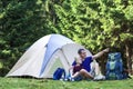 Holiday camping. Father shows his son something in distance taking rest near tent after hiking in the forest Traveling and