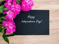 Holiday card Happy Independence Day. Pink floral assorted pink flower on wooden background with black paper free space, copy space