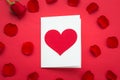 Holiday Card. Heart for Valentines day. Close up Small White Card with I Love You Message and Red Rose Flower on Top of the red ba Royalty Free Stock Photo