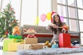 Holiday celebration season`s greetings Concept. Smiling asian woman wrapping and decorate gift box by festive ribbon in living Royalty Free Stock Photo