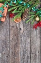 Holiday Christmas card with fir branches, Holly berries, dried oranges, gift, etc. on rustic wooden background. Royalty Free Stock Photo