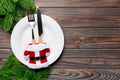 Holiday composition of plate and flatware decorated with Santa clothes on wooden background. Top view of Christmas decorations Royalty Free Stock Photo