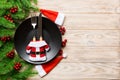 Holiday composition of plate and flatware decorated with Santa hat and clothes on wooden background. Top view of Christmas Royalty Free Stock Photo
