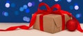 Holiday concept. Banner of christmas gift box with red bow and christmas red ball on blue bokeh background. Royalty Free Stock Photo