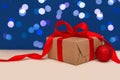 Holiday concept. Christmas gift box with red bow and christmas red ball on blue bokeh background. Holiday greeting card. Copy Royalty Free Stock Photo