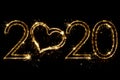 Holiday concept. Number 2020 with heart decor written sparkling sparklers isolated on black background. Overlay templatefor for Royalty Free Stock Photo