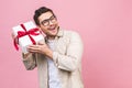 Holiday concept. Portrait of a young man opening gift box isolated over pink background Royalty Free Stock Photo