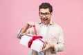 Holiday concept. Portrait of a young man opening gift box isolated over pink background Royalty Free Stock Photo