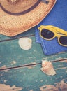 Holiday Concept: Vintage wood table with holiday accessories: Straw hat, sunglasses, flip flops, shells, vintage camera, towel and