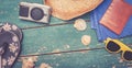 Holiday Concept: Vintage wood table with holiday accessories: Straw hat, sunglasses, flip flops, shells, vintage camera, towel and