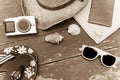 Holiday Concept: Vintage wood table with holiday accessories: Straw hat, sunglasses, flip flops, shells, vintage camera, towel and