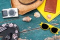 Holiday Concept: Vintage wood table with holiday accessories: Straw hat, sunglasses, flip flops, shells, vintage camera, towel and