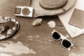 Holiday Concept: Vintage wood table with holiday accessories: Straw hat, sunglasses, flip flops, shells, vintage camera, towel and