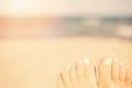 Holiday concept. Woman feet close-up relaxing on beach, enjoying sun and splendid view. Sandy feet on the beach. Sun, sun haze